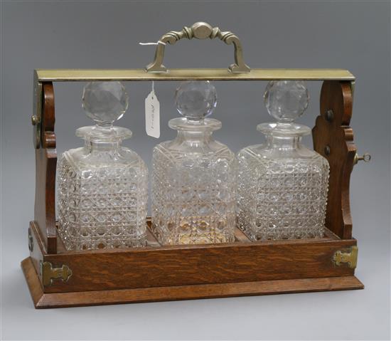An Edwardian Betjemann three bottle oak tantalus length 41cm
